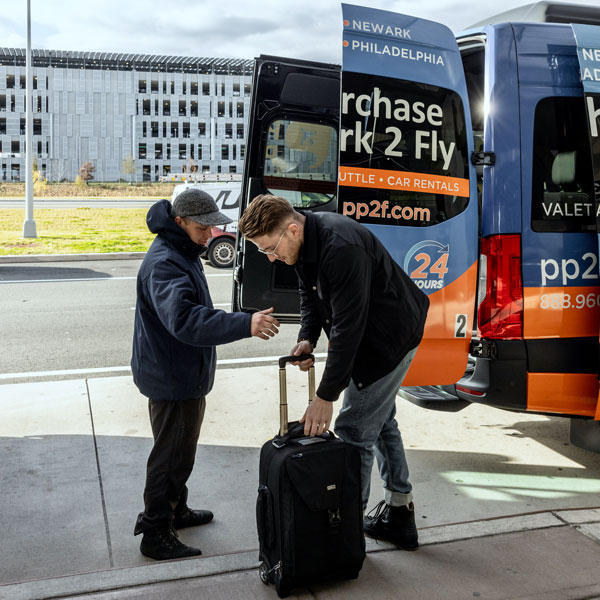 man helping passenger with luggage behind shuttle