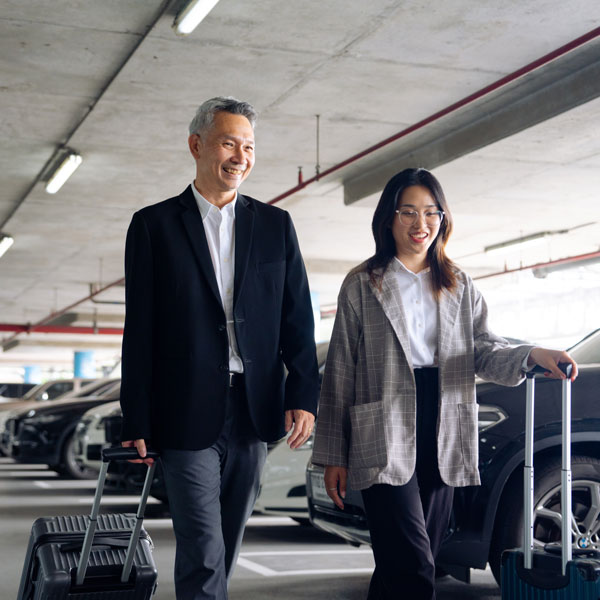 man and woman walking with luggage through garage